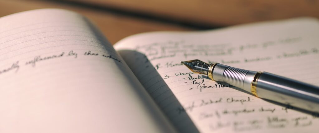 Füllfeder auf aufgeschlagenem Tagebuch mit handschriftlichem Text