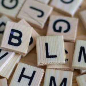 Scrabble Holzsteine mit Buchstaben darauf auf Holztisch ausgebreitet