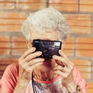 Alte Frau mit kleiner Kamera vor dem Gesicht